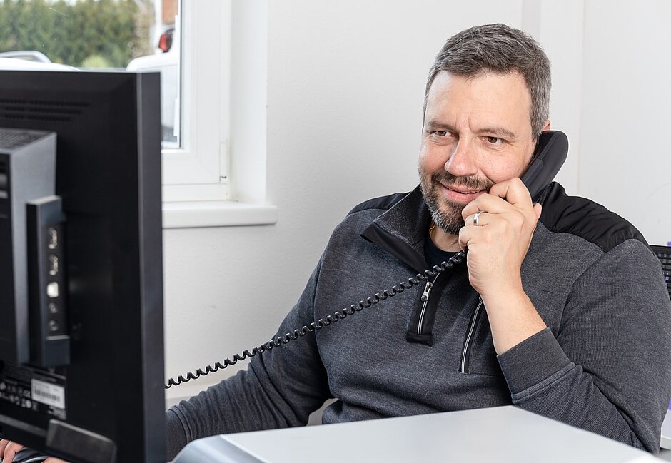 Mann vor Computer an Telefon